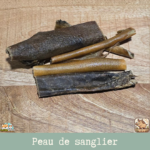 Morceaux de peau de sanglier séchée présentés sur une table.