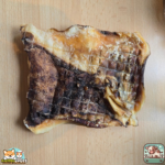 Plaque de peau de bœuf séchée présentée sur une table.