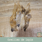 Oreilles de lapin sans poil exposées sur une surface en bois, mettant en valeur leur texture naturelle et leur couleur claire.
